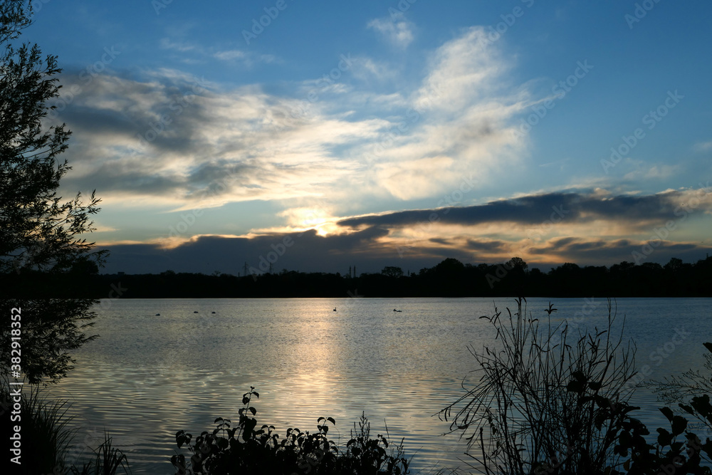 Amazing sunset over the water. Beautiful landscape with a lake and dramatic sky with cumulus clouds on the horizon. Amazing sunset over the water. Beautiful landscape with a lake and dramatic sky with cumulus clouds on the horizon.