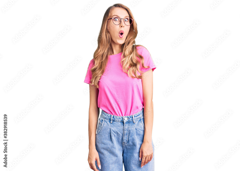 Young beautiful caucasian woman with blond hair wearing casual clothes and glasses afraid and shocked with surprise expression, fear and excited face. Young beautiful caucasian woman with blond hair wearing casual clothes and glasses afraid and shocked with surprise expression, fear and excited face.
