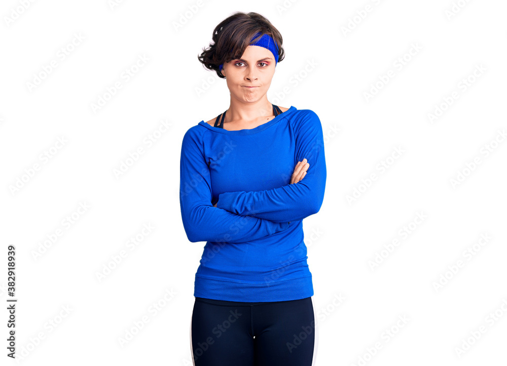 Beautiful young woman with short hair wearing training workout clothes skeptic and nervous, disapproving expression on face with crossed arms. negative person. Beautiful young woman with short hair wearing training workout clothes skeptic and nervous, disapproving expression on face with crossed arms. negative person.