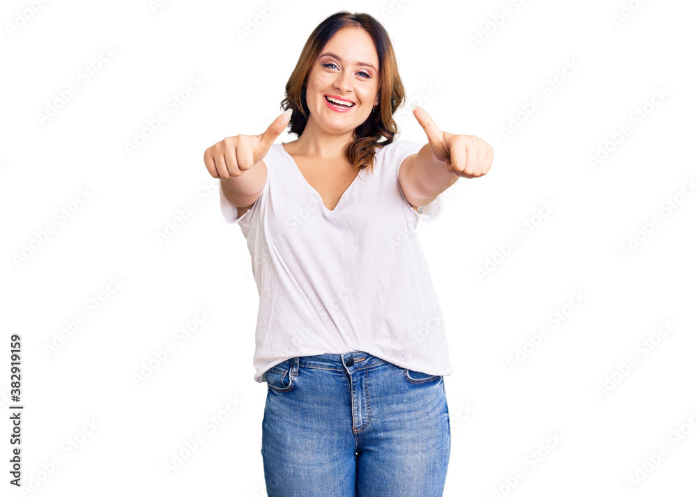 Young beautiful caucasian woman wearing casual white tshirt approving doing positive gesture with hand, thumbs up smiling and happy for success. winner gesture. Young beautiful caucasian woman wearing casual white tshirt approving doing positive gesture with hand, thumbs up smiling and happy for success. winner gesture.