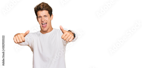 Handsome caucasian man wearing casual white sweater approving doing positive gesture with hand, thumbs up smiling and happy for success. winner gesture.