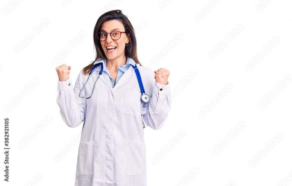 Young beautiful woman wearing doctor stethoscope and glasses celebrating surprised and amazed for success with arms raised and open eyes. winner concept. Young beautiful woman wearing doctor stethoscope and glasses celebrating surprised and amazed for success with arms raised and open eyes. winner concept.