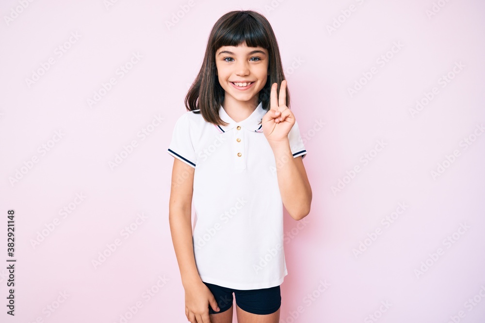 Young little girl with bang wearing sportswear smiling with happy face winking at the camera doing victory sign. number two.