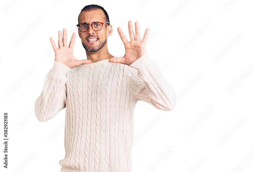 Young handsome man wearing casual clothes and glasses afraid and terrified with fear expression stop gesture with hands, shouting in shock. panic concept. Young handsome man wearing casual clothes and glasses afraid and terrified with fear expression stop gesture with hands, shouting in shock. panic concept.