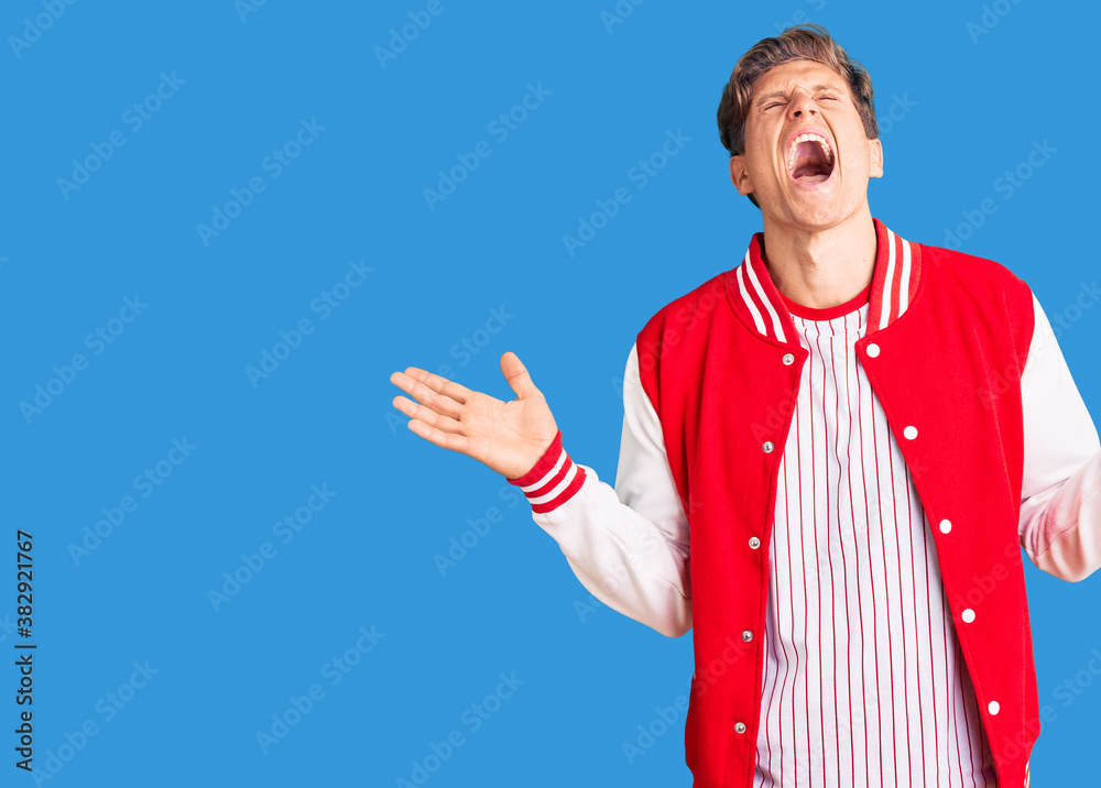 Young handsome man wearing baseball uniform celebrating mad and crazy for success with arms raised and closed eyes screaming excited. winner concept Young handsome man wearing baseball uniform celebrating mad and crazy for success with arms raised and closed eyes screaming excited. winner concept