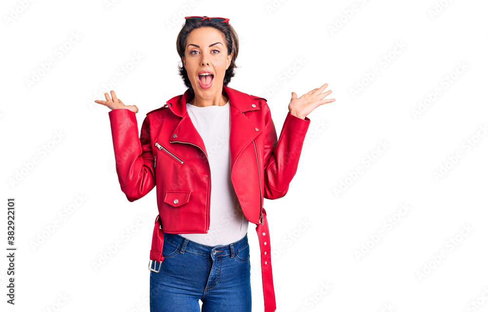 Young beautiful woman wearing red leather jacket celebrating crazy and amazed for success with arms raised and open eyes screaming excited. winner concept