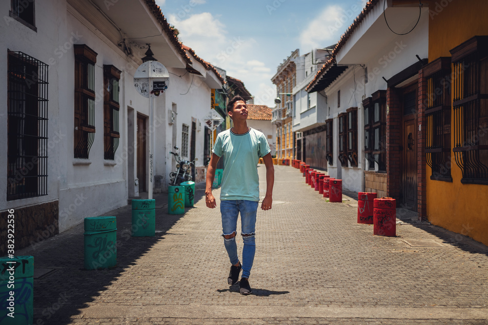Naklejka premium portrait of young man walking down street of old house