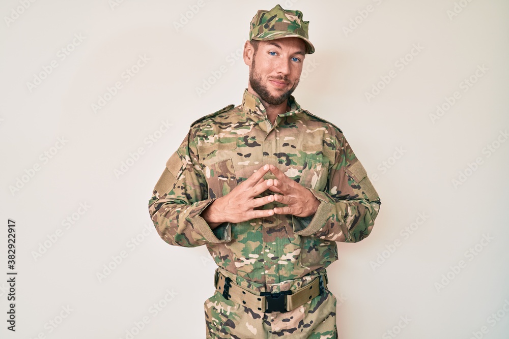 Young caucasian man wearing camouflage army uniform hands together and fingers crossed smiling relaxed and cheerful. success and optimistic Young caucasian man wearing camouflage army uniform hands together and fingers crossed smiling relaxed and cheerful. success and optimistic