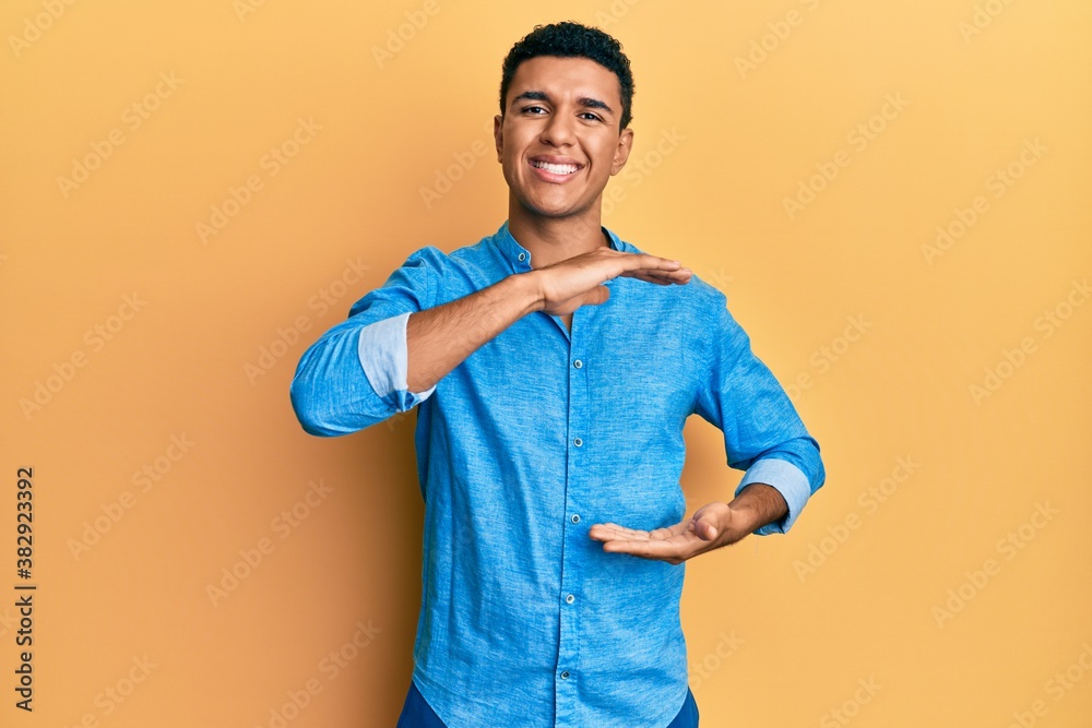 Young arab man wearing casual clothes gesturing with hands showing big and large size sign, measure symbol. smiling looking at the camera. measuring concept. Young arab man wearing casual clothes gesturing with hands showing big and large size sign, measure symbol. smiling looking at the camera. measuring concept.