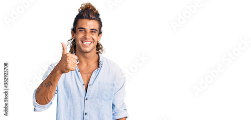 Young hispanic man wearing summer style doing happy thumbs up gesture with hand. approving expression looking at the camera showing success.