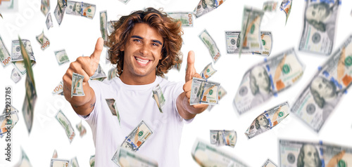 Young hispanic man wearing casual white tshirt approving doing positive gesture with hand, thumbs up smiling and happy for success. winner gesture. photo