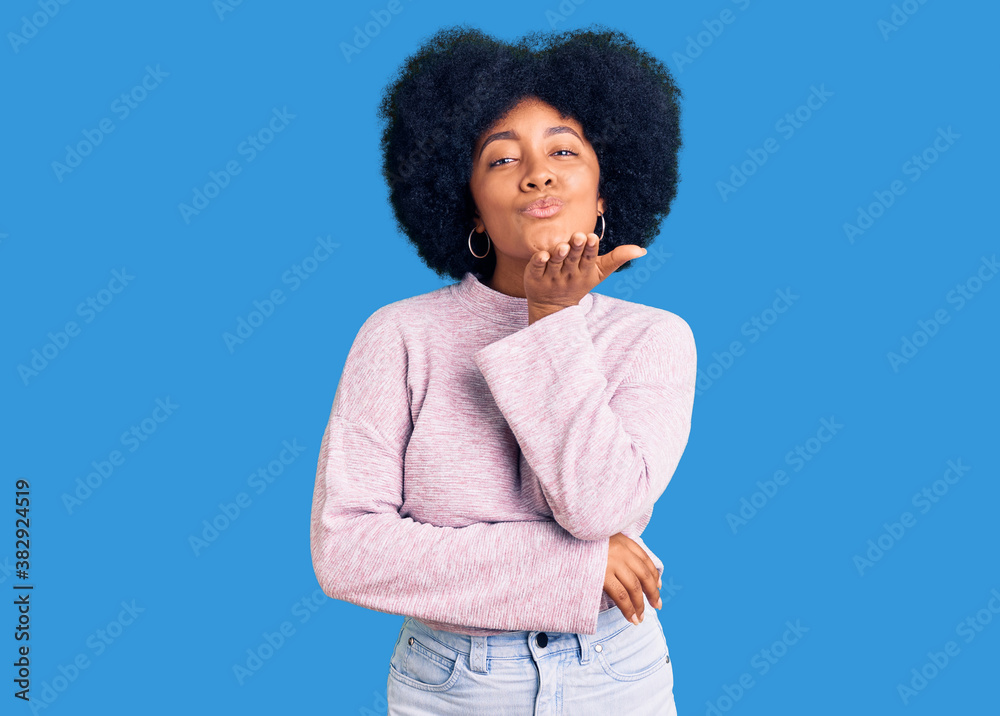 Young african american girl wearing casual clothes looking at the camera blowing a kiss with hand on air being lovely and sexy. love expression. Young african american girl wearing casual clothes looking at the camera blowing a kiss with hand on air being lovely and sexy. love expression.