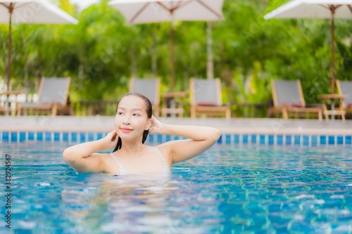 Portrait beautiful young asian woman smile relax around outdoor swimming pool in resort