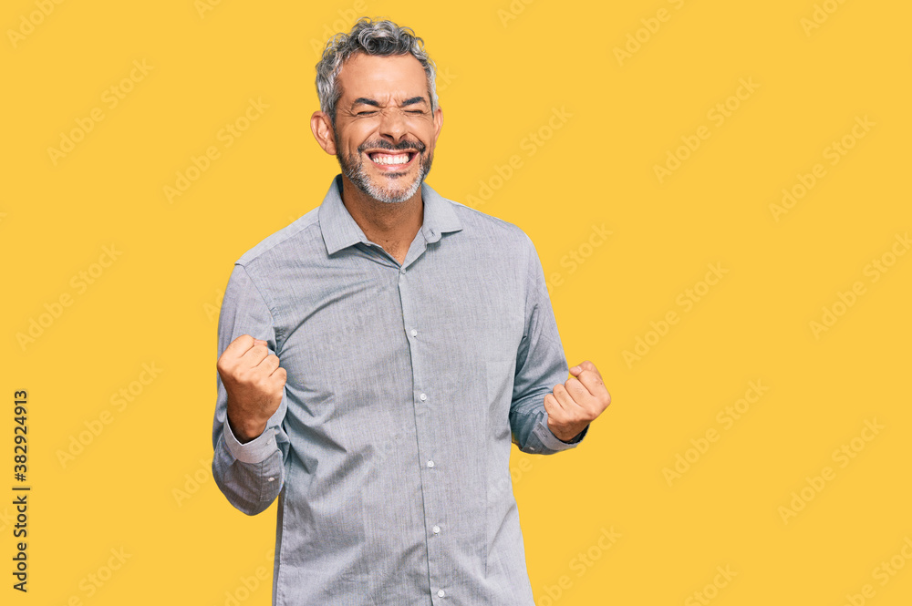 Middle age grey-haired man wearing casual clothes very happy and excited doing winner gesture with arms raised, smiling and screaming for success. celebration concept. Middle age grey-haired man wearing casual clothes very happy and excited doing winner gesture with arms raised, smiling and screaming for success. celebration concept.