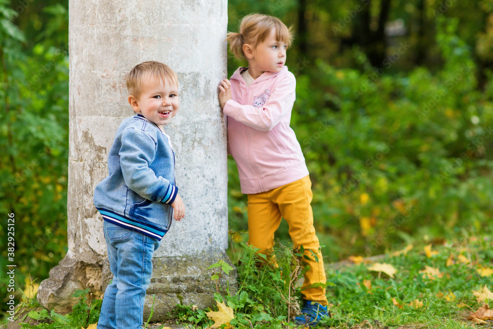 .Children play near the column in the old park on an autumn walk .Children play near the column in the old park on an autumn walk