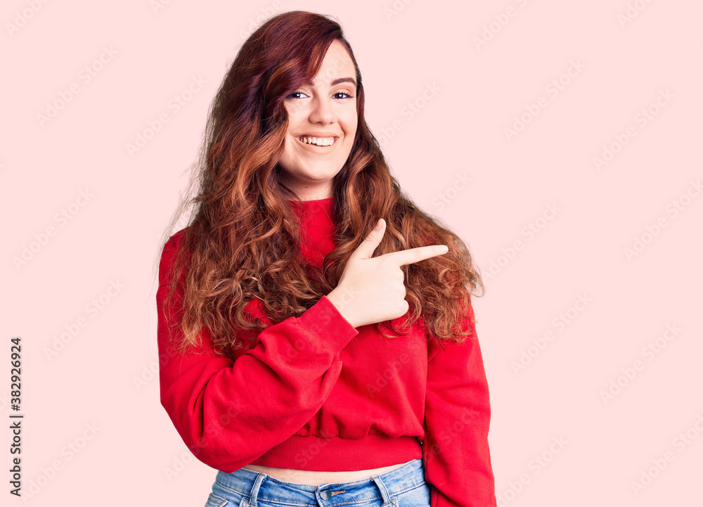 Fototapeta premium Young beautiful woman wearing casual winter sweater cheerful with a smile of face pointing with hand and finger up to the side with happy and natural expression on face