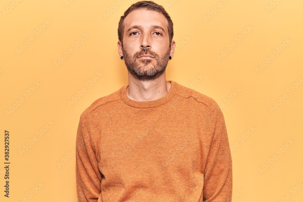 Young handsome man wearing casual clothes with serious expression on face. simple and natural looking at the camera. Young handsome man wearing casual clothes with serious expression on face. simple and natural looking at the camera.