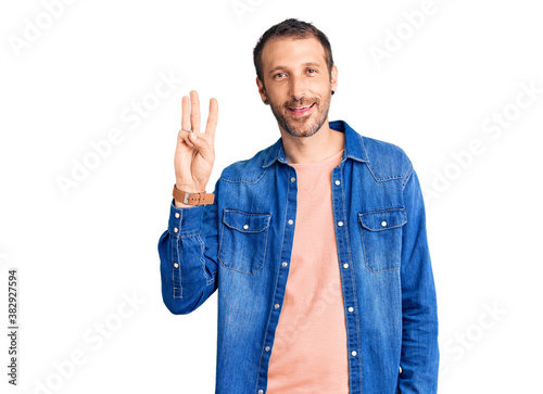 Young handsome man wearing casual clothes showing and pointing up with fingers number three while smiling confident and happy.