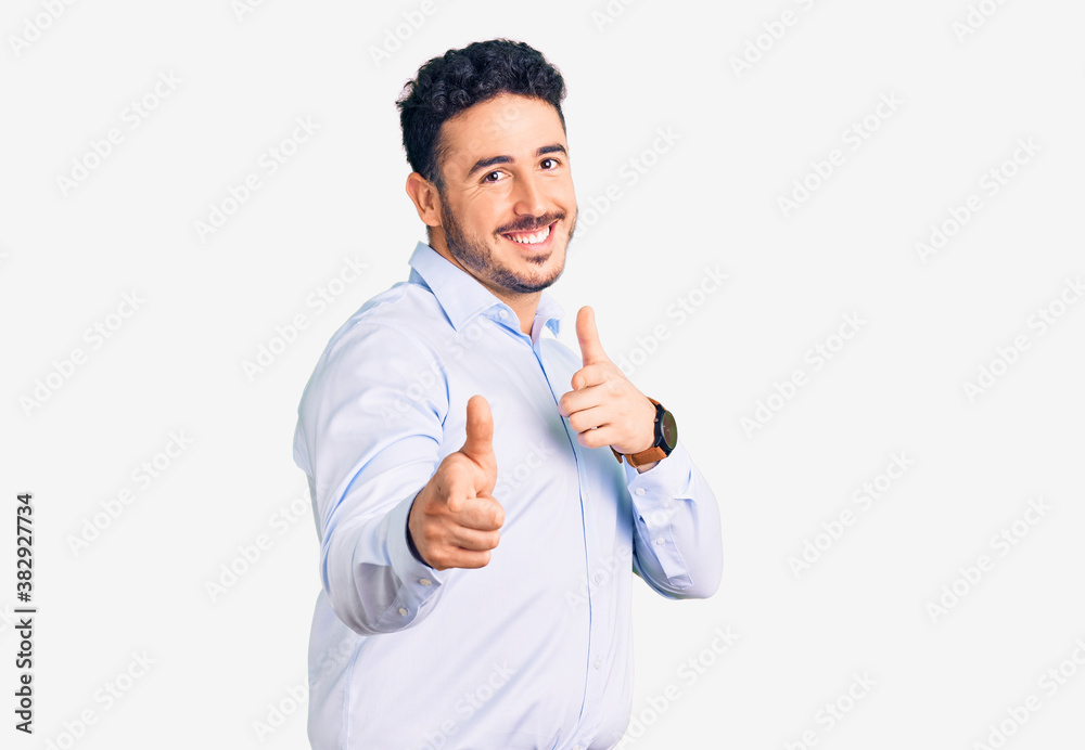 Young hispanic man wearing business clothes pointing fingers to camera with happy and funny face. good energy and vibes. Young hispanic man wearing business clothes pointing fingers to camera with happy and funny face. good energy and vibes.