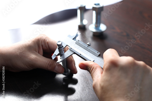 The worker is measuring to outer diameter of bolt with vernier caliper gauge. Vernier calipers are widely used in scientific laboratories and in manufacturing for quality control measurements.