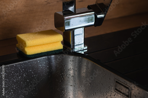 Clean washing sponge sitting on the edge of the black sink in the kitchen. 