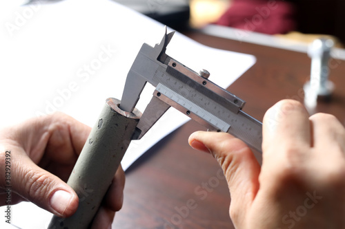 The worker is measuring to wall thickness of metal small pipe with vernier caliper gauge. Vernier calipers are widely used in scientific laboratories and in manufacturing for quality control.