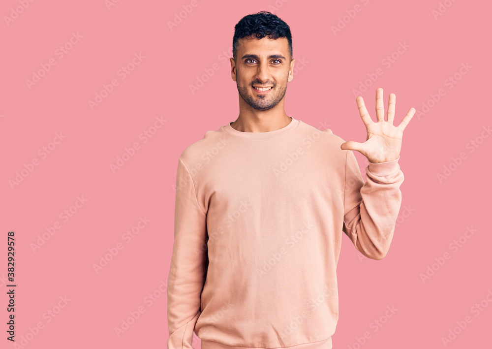 Young hispanic man wearing casual clothes showing and pointing up with fingers number five while smiling confident and happy.