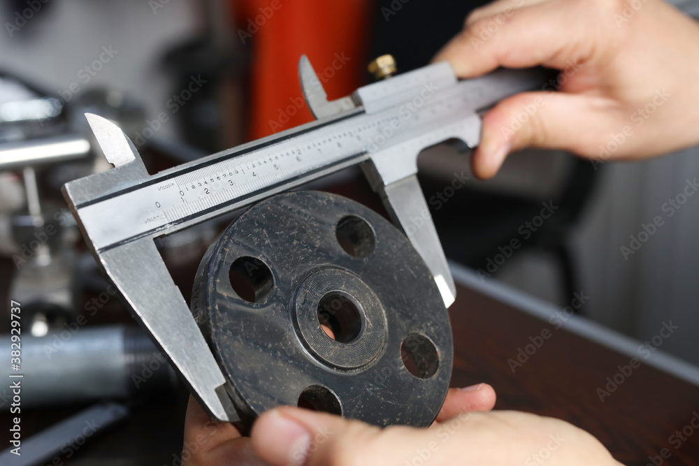 The worker is measuring to outer diameter of flange with vernier