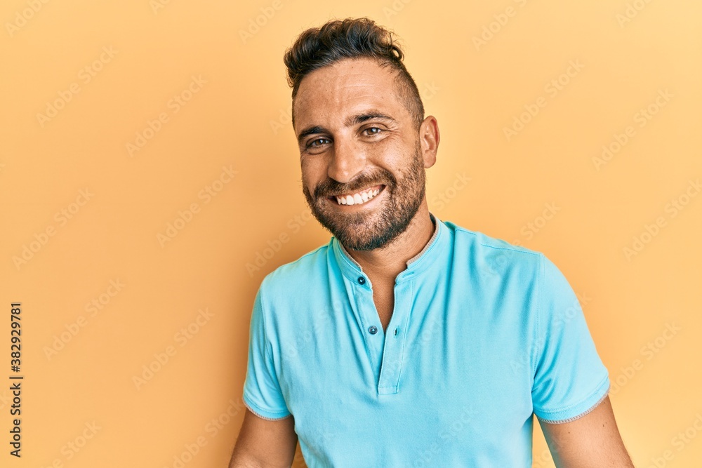 Handsome man with beard wearing casual clothes looking positive and happy standing and smiling with a confident smile showing teeth Handsome man with beard wearing casual clothes looking positive and happy standing and smiling with a confident smile showing teeth