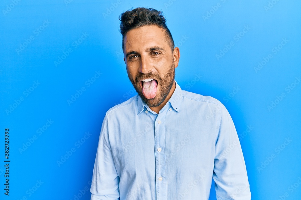 Handsome man with beard wearing casual clothes sticking tongue out happy with funny expression. emotion concept. Handsome man with beard wearing casual clothes sticking tongue out happy with funny expression. emotion concept.