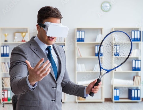 Businessman playing virtual reality tennis in office with VR gog