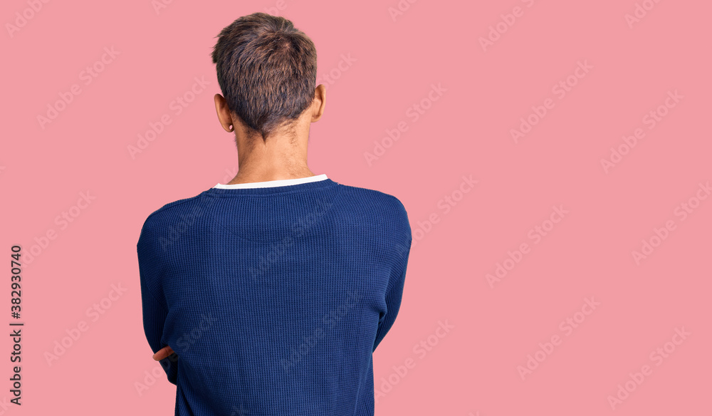 Handsome blond man with beard wearing casual sweater standing backwards looking away with crossed arms Handsome blond man with beard wearing casual sweater standing backwards looking away with crossed arms