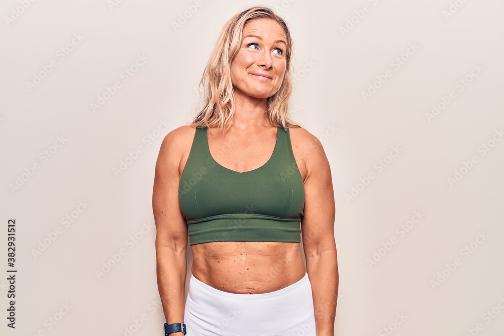 Middle age caucasian blonde woman wearing sportswear smiling looking to the side and staring away thinking. Middle age caucasian blonde woman wearing sportswear smiling looking to the side and staring away thinking.