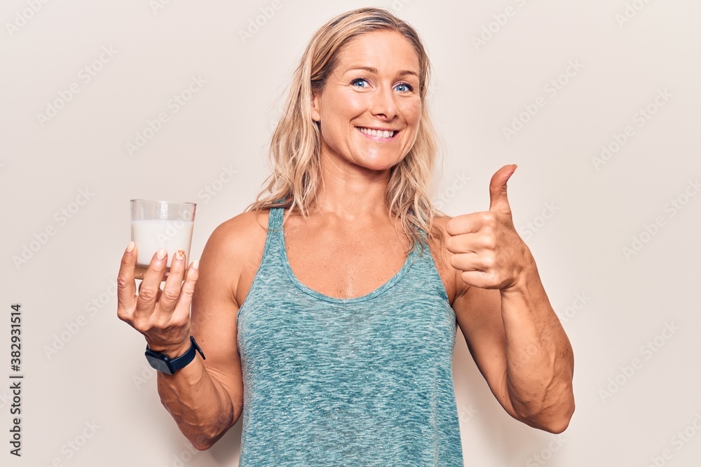 Middle age caucasian blonde woman holding a glass of milk smiling happy and positive, thumb up doing excellent and approval sign Middle age caucasian blonde woman holding a glass of milk smiling happy and positive, thumb up doing excellent and approval sign