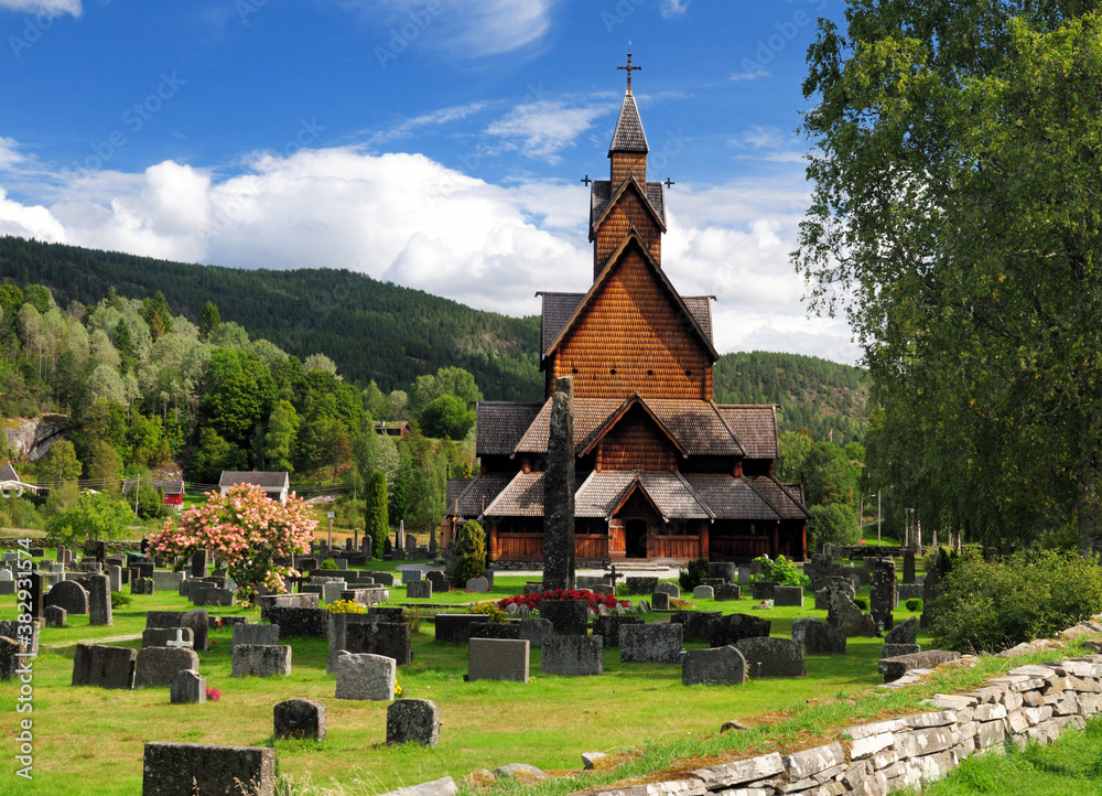 View From The Cemetery To The Largest Stave Church Of Norway In Heddal On A Sunny Summer Day With A Clear Blue Sky And A Few Clouds View From The Cemetery To The Largest Stave Church Of Norway In Heddal On A Sunny Summer Day With A Clear Blue Sky And A Few Clouds