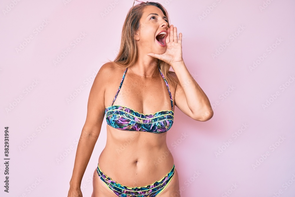 Naklejka premium Middle age hispanic woman wearing bikini shouting and screaming loud to side with hand on mouth. communication concept.