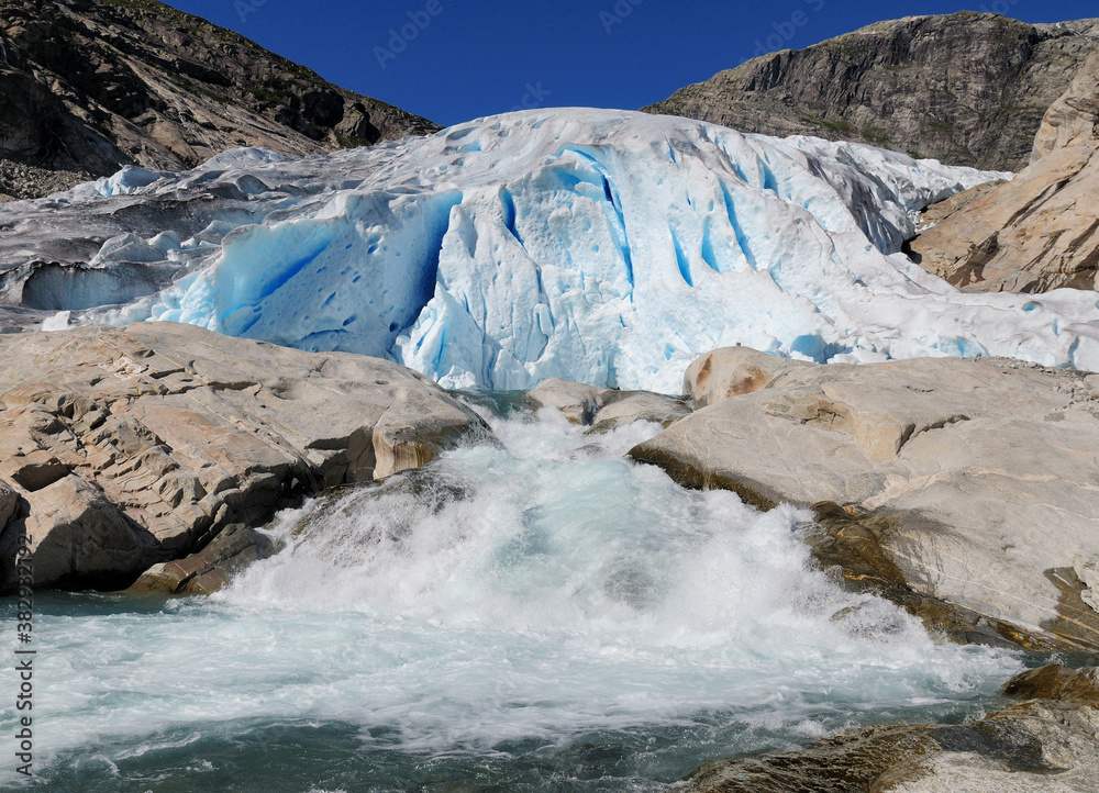 Water Splashing At The Bottom Of The Glacier Nigardsbreen In Jostedalsbreen National Park On A Sunny Summer Day With A Clear Blue Sky