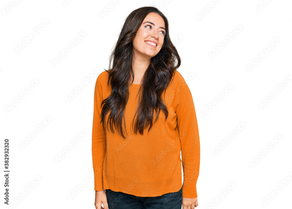 Beautiful brunette young woman wearing casual orange sweater looking away to side with smile on face, natural expression. laughing confident. Beautiful brunette young woman wearing casual orange sweater looking away to side with smile on face, natural expression. laughing confident.