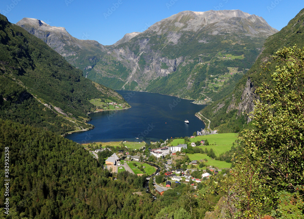 View From Flydalsjuvet Lookout To Geiranger Village And Geirangerfjord On A Sunny Summer Day With A Clear Blue Sky