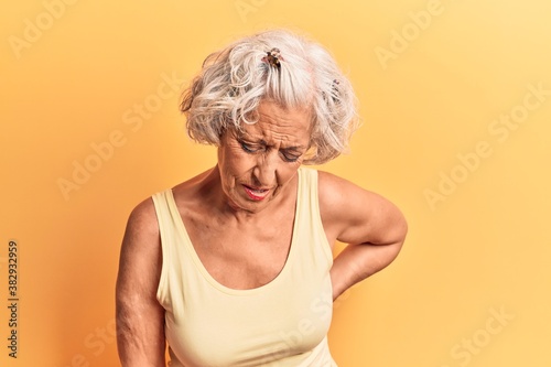 Senior grey-haired woman wearing casual clothes suffering of backache, touching back with hand, muscular pain