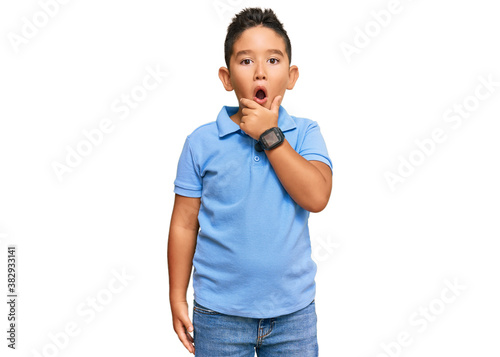 Little boy hispanic kid wearing casual clothes looking fascinated with disbelief, surprise and amazed expression with hands on chin