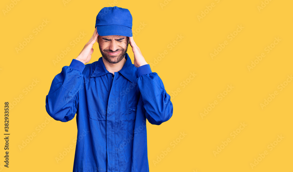 Young hispanic man wearing painter uniform suffering from headache desperate and stressed because pain and migraine. hands on head.