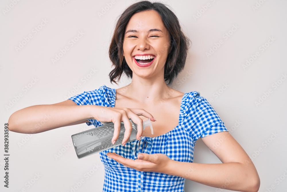 Young beautiful woman using hand sanitizer gel smiling and laughing hard out loud because funny crazy joke. Young beautiful woman using hand sanitizer gel smiling and laughing hard out loud because funny crazy joke.