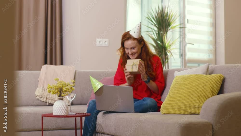 Pretty caucasian girl with ginger hair speaking with parents on online communicating laptop videochat conference giving present and rejoicing. Birthday congratulations. Quarantine. Home atmosphere. Pretty caucasian girl with ginger hair speaking with parents on online communicating laptop videochat conference giving present and rejoicing. Birthday congratulations. Quarantine. Home atmosphere.