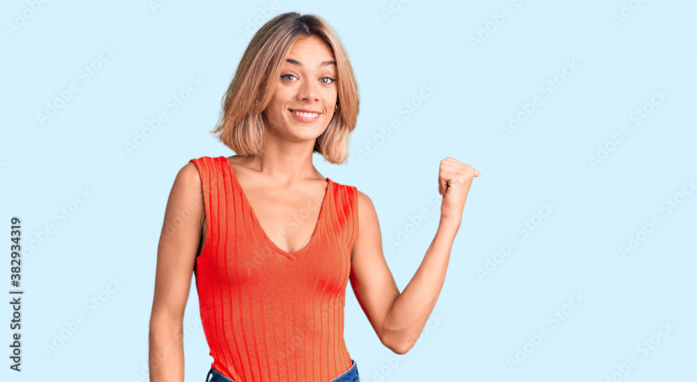 Beautiful caucasian woman wearing casual clothes smiling with happy face looking and pointing to the side with thumb up. Beautiful caucasian woman wearing casual clothes smiling with happy face looking and pointing to the side with thumb up.