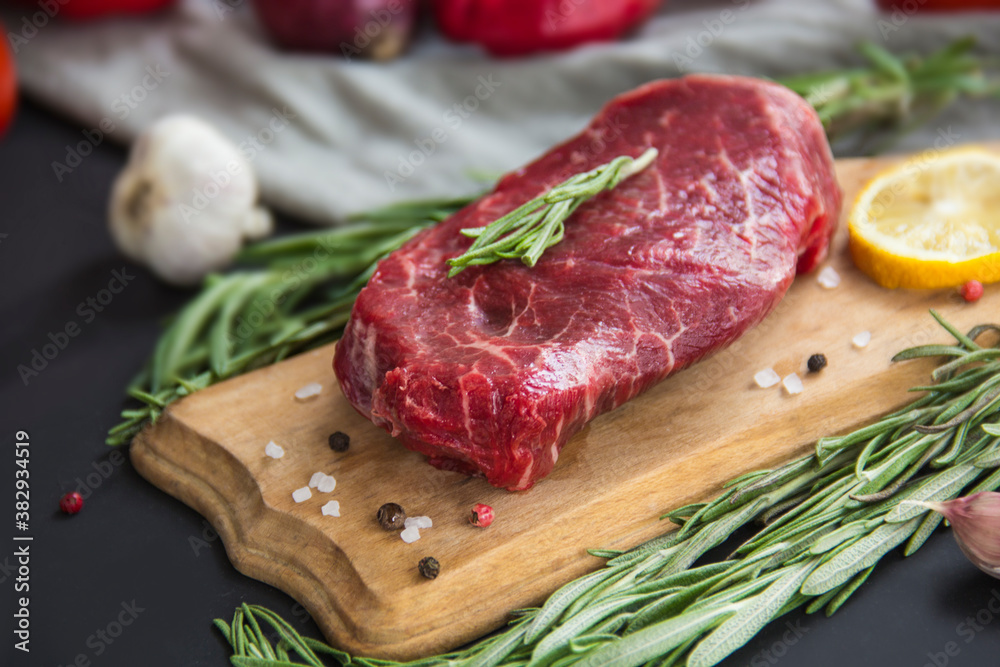 Raw beef steak on a cutting board with spices. Creative atmospheric decoration