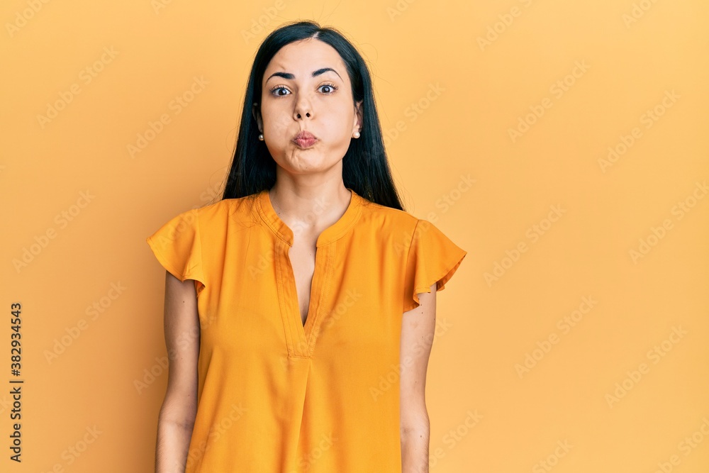 Fototapeta premium Beautiful young woman wearing casual clothes puffing cheeks with funny face. mouth inflated with air, crazy expression.