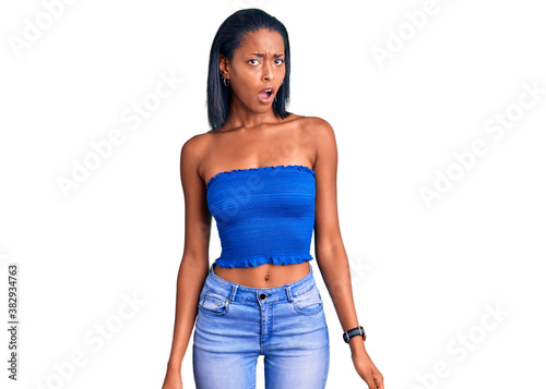 Young african american woman wearing casual summer clothes in shock face, looking skeptical and sarcastic, surprised with open mouth photo