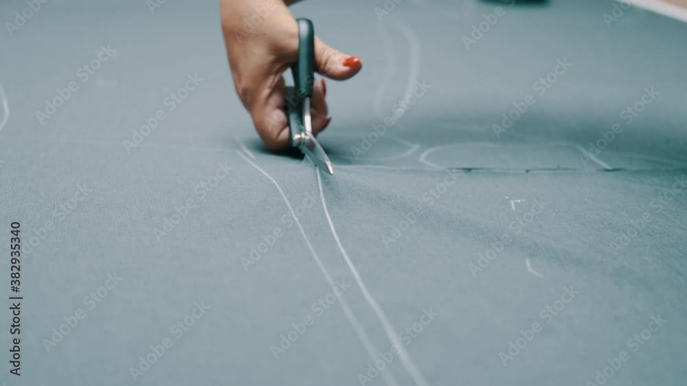 Woman cuts dark fabric with scissors