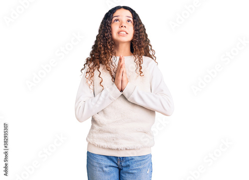 Beautiful kid girl with curly hair wearing casual clothes begging and praying with hands together with hope expression on face very emotional and worried. begging. © Krakenimages.com